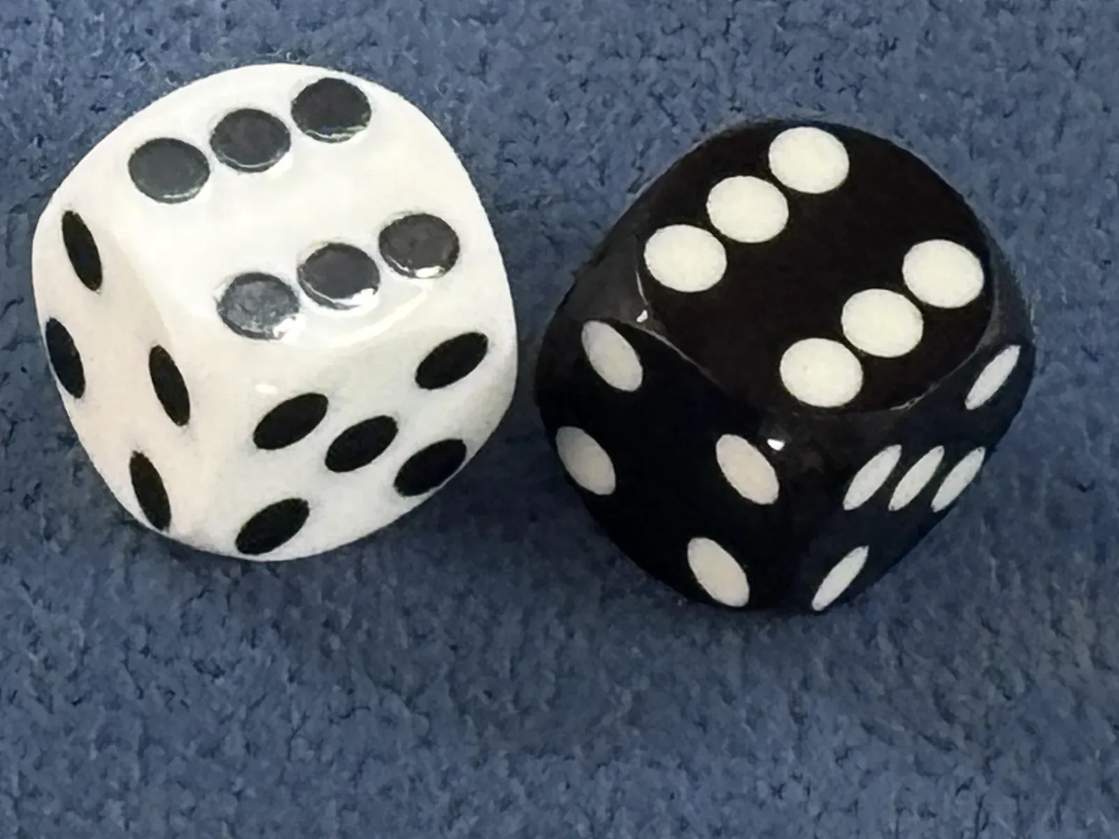 A white and a black die with rounded corners on blue felt